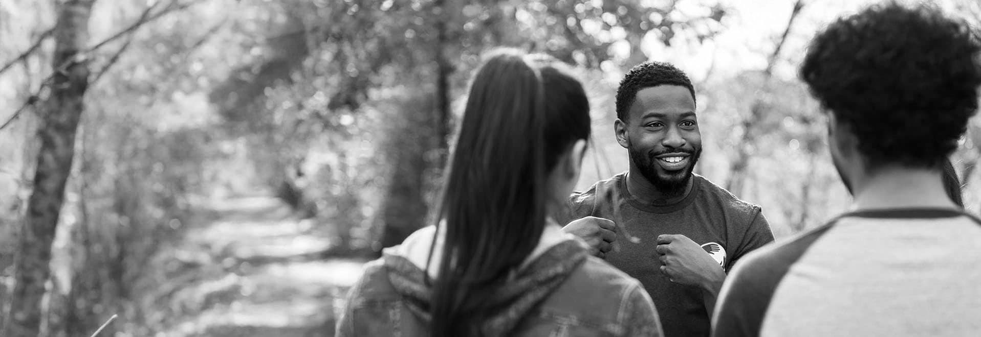 Man facing the camera and smiling while conversing with three other people